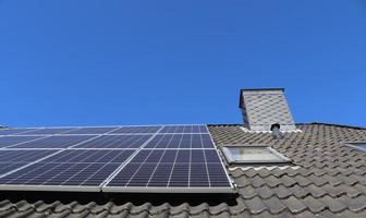 Solar panels producing clean energy on a roof of a residential house photo