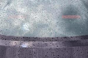 Rain drops on a black metallic car surface in a closeup view. photo