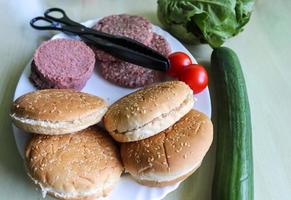 Homemade making of a grilled burger with tomatoes and salad on a plate photo