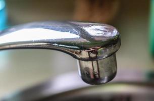 Running water from a water tap into the drain of a chrome sink. photo