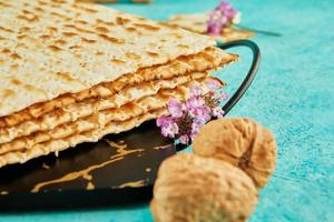 Pesach celebration concept - jewish Passover holiday. Matzah on stand made of marble with walnuts and wildflowers