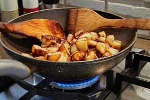 Frying pan with fried potatoes on gas stove. Step by step recipe photo