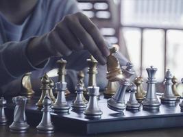 Hand businessman moving the golden knight chess fighting silver knight with fire sparks chess on chess board to successfully in the competition. Management or leadership strategy and teamwork concept. photo