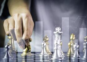 Hand businessman moving the golden knight chess fighting silver knight with fire sparks chess on chess board to successfully in the competition. Management or leadership strategy and teamwork concept. photo