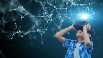 Boy wearing virtual reality glasses in modern interior design studio and trying to touch dots network and earth map or something appear in VR with exciting.Flares effect, blurred background concept. photo