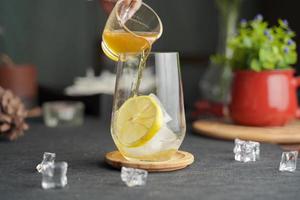 Glass of espresso with lemon juice and fresh sliced lemon on wooden table and copy space, Summer Cocktail, Cold brew coffee or black tea.Pouring cold drink.