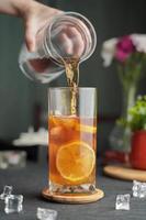 Glass of espresso with lemon juice and fresh sliced lemon on wooden table and copy space, Summer Cocktail, Cold brew coffee or black tea,Pouring cold drink. photo