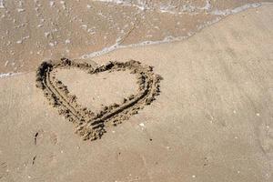 A drawing of a heart on a yellow sand at a beautiful seascape background. Horizontal composition. photo