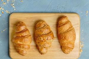 croissants recién horneados en placa de madera, vista superior. croissants franceses y americanos y pasteles horneados se disfrutan en todo el mundo. foto