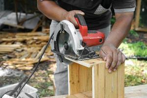 el carpintero asiático está aserrando la madera. foto