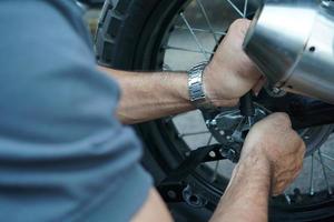 cierre la mano del trabajador técnico, la rueda fija de la motocicleta en el exterior del garaje. foto