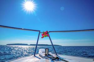 la parte delantera del barco se conduce en el mar con el día soleado a la isla frente a él. foto