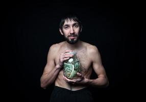 Young man with money bottle on black background photo