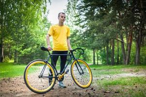 un joven se detuvo a descansar con su bicicleta en un parque público. foto