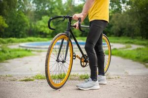 un joven se detuvo a descansar con su bicicleta en un parque público. foto