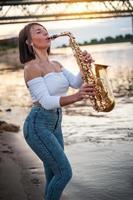 mujer tocando el saxofón al atardecer foto