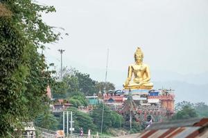 very big great gold buddha statue sitting beside river photo
