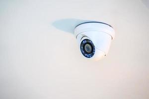 white CCTV camera hang on to the ceiling. photo