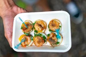 fried Quail eggs top up with boiled and fried shrimp, in the paper plate and plastic fork. photo