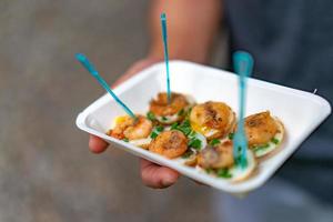 fried Quail eggs top up with boiled and fried shrimp, in the paper plate and plastic fork. photo