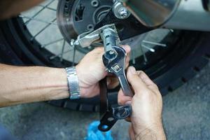 cierre la mano del trabajador técnico, la rueda fija de la motocicleta en el exterior del garaje. foto