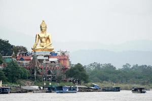 very big great gold buddha statue sitting beside river photo