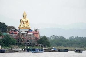 estatua de buda de oro muy grande sentada al lado del río foto