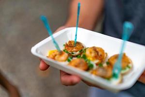 fried Quail eggs top up with boiled and fried shrimp, in the paper plate and plastic fork. photo