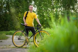 A young Man stopped to rest With his Bicycle in a public Park. photo