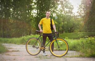 un joven se detuvo a descansar con su bicicleta en un parque público. foto