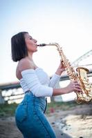 Woman playing the saxophone at sunset. photo