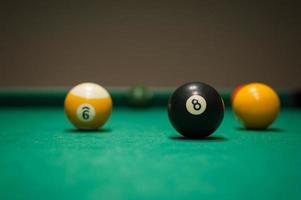 bolas de billar deportivas dispuestas en forma de triángulo en una mesa de billar verde en el pub foto