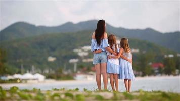 bella madre y sus adorables hijitas en la playa al atardecer