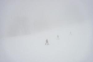 Skiers on the slopes in misty day photo