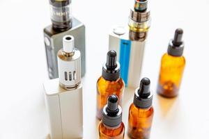 Vaping device e-cigarette electronic cigarette and liquid bottles isolated on white background. Vape device for alternative smoking. Vaping shop concept. Gadget for vaper. Vaping accessories. photo