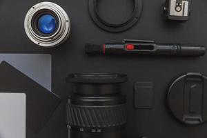 lugar de trabajo del fotógrafo con sistema de cámara dslr, kit de limpieza de cámara, lente y accesorio de cámara sobre fondo de mesa negro oscuro. concepto de fotografía de viajes de hobby espacio de copia de vista superior endecha plana foto