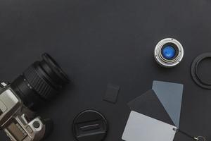 Photographer workplace with dslr camera system, camera cleaning kit, lens and camera accessory on dark black table background. Hobby travel photography concept Flat lay top view copy space photo