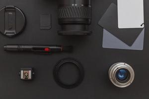 Photographer workplace with dslr camera system, camera cleaning kit, lens and camera accessory on dark black table background. Hobby travel photography concept. Flat lay top view copy space. photo