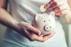 Woman hands holding pink piggy bank and putting money Euro coin photo
