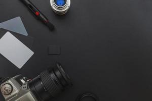Photographer work place work space with dslr camera system, camera cleaning kit, lens and camera accessory on dark black background. Hobby travel photography concept. Flat lay top view, copy space photo