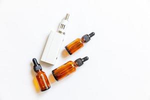 Vaping device e-cigarette electronic cigarette and liquid bottles isolated on white background. Vape device for alternative smoking. Vaping shop concept. Gadget for vaper. Vaping accessories. photo