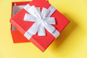 navidad año nuevo cumpleaños san valentín celebración presente concepto romántico. caja de regalo roja de diseño simplemente minimalista aislada sobre fondo amarillo colorido. espacio de copia de vista superior plana. foto