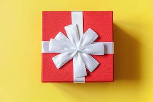 navidad año nuevo cumpleaños san valentín celebración presente concepto romántico. caja de regalo roja de diseño simplemente minimalista aislada sobre fondo amarillo colorido. espacio de copia de vista superior plana. foto