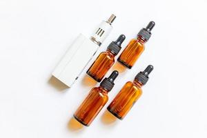 dispositivo de vapeo e-cigarrillo cigarrillo electrónico y botellas de líquido aisladas sobre fondo blanco. dispositivo vape para fumar alternativo. concepto de tienda de vapeo. artilugio para vaper. accesorios de vapeo foto