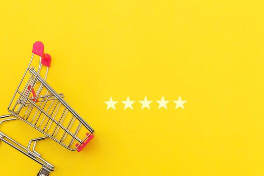 Small supermarket grocery push cart for shopping toy with wheels and 5 stars rating isolated on yellow background. Retail consumer buying online assessment and review concept. photo