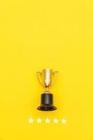 Simply flat lay design winner or champion gold trophy cup and 5 stars rating isolated on pink pastel background. Victory first place of competition. Winning or success concept. Top view copy space.