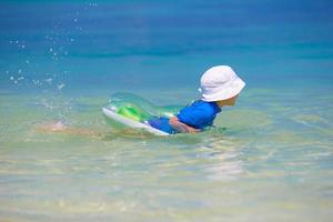 Adorable little girl playing in shallow water on white beach