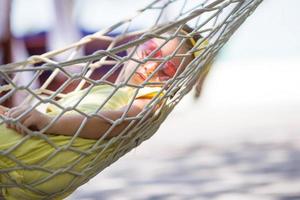 Adorable little girl on tropical vacation relaxing in hammock