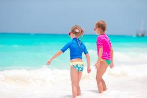 Adorable little girls at beach having fun in shallow water during summer vacation