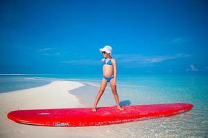 Little adorable girl practice surfing position at beach